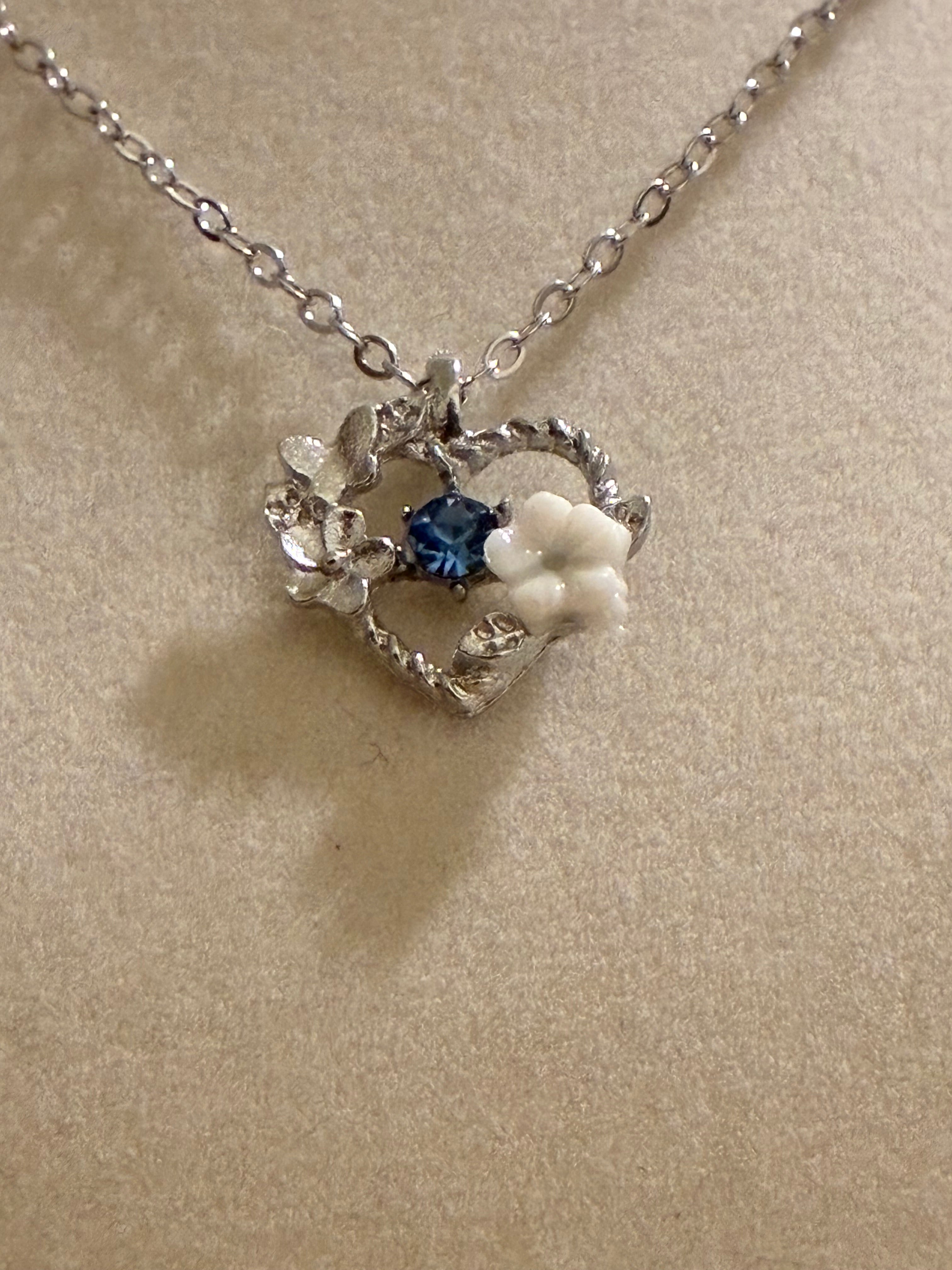 Silver plated heart pendant with a blue stone and white floral charm