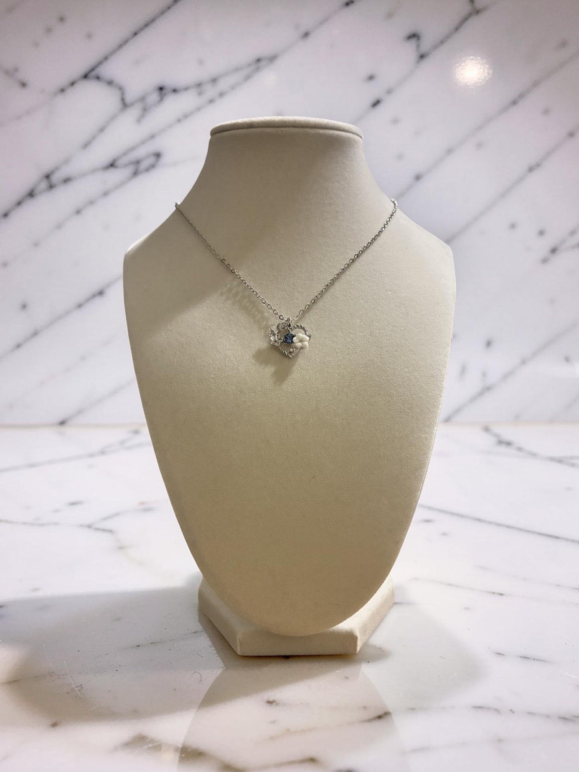 Silver plated heart pendant with a blue stone and white floral charm